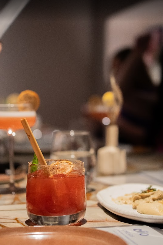 pink drink on a restaurant table with a lemon garnish and paper straw